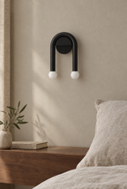 Svart bågformad vägglampa med två vita glober