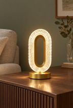 Oval bordslampa med klar facetterad ring och guldfärgad fot