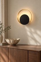 Vägglampa med guldfärgad ring och svart skiva